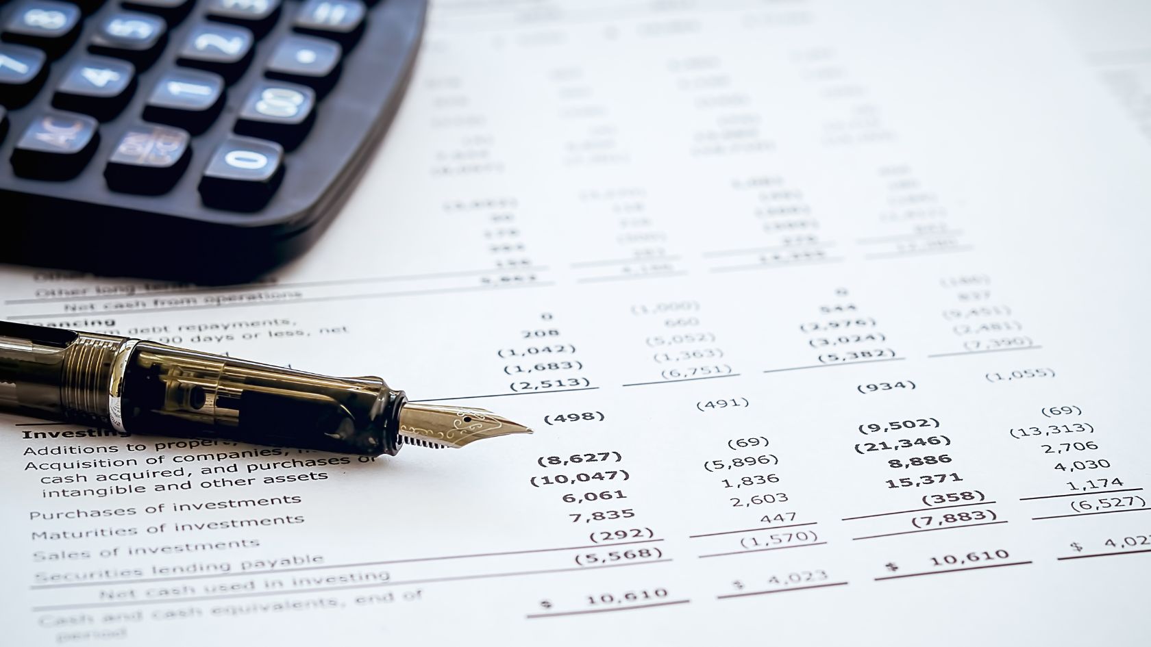 pen and calculator on top of a sheet of numbers